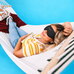 Woman resting in a hammock wearing a black 3D sleep mask