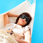Woman resting in a hammock wearing a black silk sleep mask