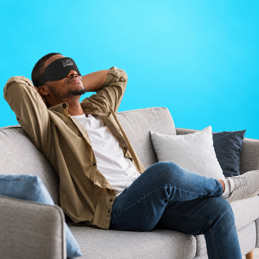 Man relaxing on a sofa wearing a black Bluetooth sleep mask